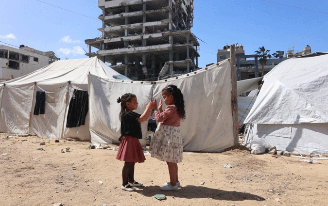 Des jeunes filles palestiniennes jouent pendant qu'elles célèbrent l'Aïd el-Fitr, qui marque la fin du mois de jeûne sacré du Ramadan, à Gaza, le 30 mars 2025. (Photo par Omar AL-QATTAA / AFP)